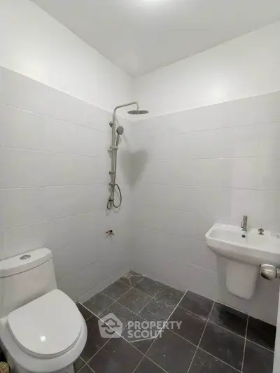 Modern minimalist bathroom with sleek fixtures and tiled walls.