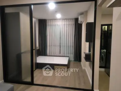 Modern bedroom with sliding glass doors and wooden flooring in a stylish apartment.