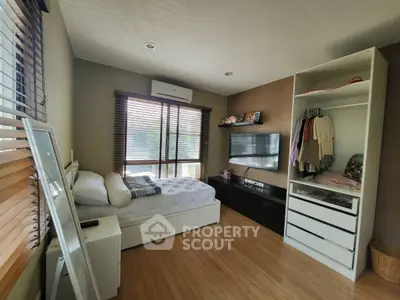 Cozy bedroom with modern decor, featuring a large window and ample storage space.