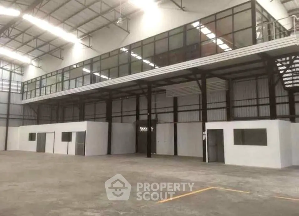 Spacious industrial warehouse with mezzanine office space and high ceilings.