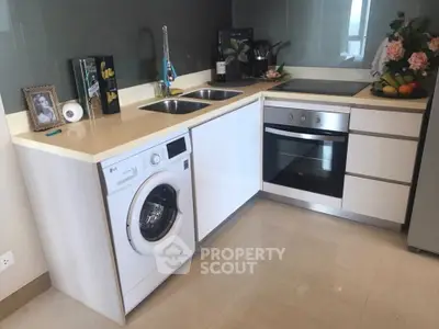 Modern kitchen with sleek appliances and dual sinks, featuring a washing machine and built-in oven.