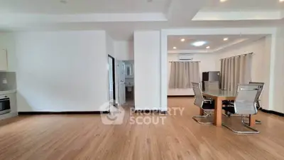 Spacious open-plan living and dining area with modern furnishings and wooden flooring.