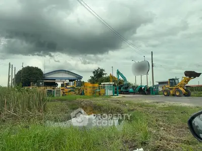 Industrial site with heavy machinery and overcast sky, showcasing construction equipment and rural landscape.