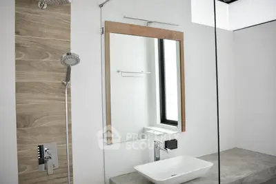 Modern bathroom with sleek fixtures and large mirror, featuring a stylish showerhead and contemporary sink.