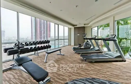 Spacious gym with modern equipment and panoramic city views in luxury building.