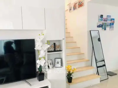 Modern living room with sleek TV, elegant staircase, and stylish decor