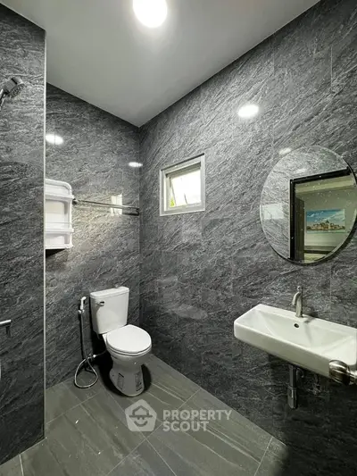 Modern bathroom with sleek gray tiles and round mirror