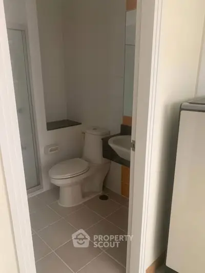 Compact bathroom with modern fixtures and tiled flooring.