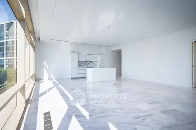 Spacious modern living room with open kitchen and large windows offering abundant natural light.