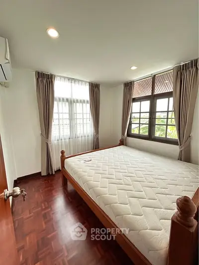 Spacious bedroom with large windows and wooden flooring, perfect for natural light lovers.