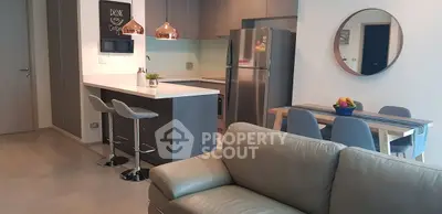 Modern open-plan living room and kitchen with stylish decor and stainless steel appliances.