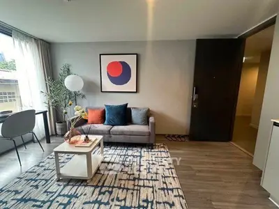 Modern living room with stylish decor, featuring a cozy sofa, abstract art, and natural light.