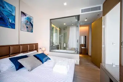 Modern bedroom with glass wall overlooking stylish bathroom in luxury apartment.