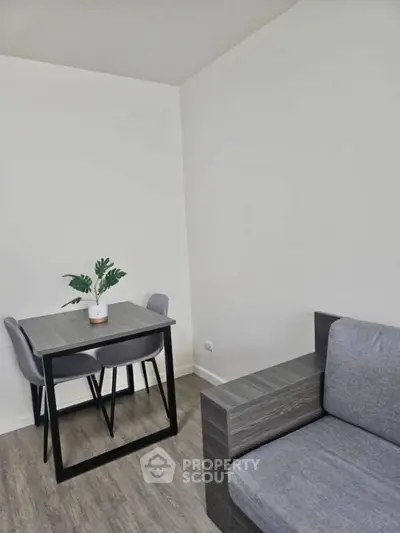Modern minimalist living room with sleek gray furniture and stylish dining set.