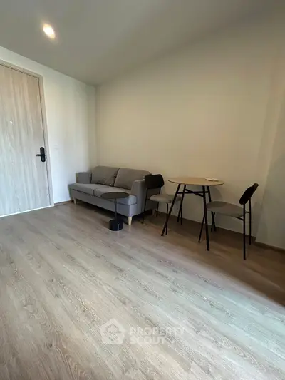 Modern living room with cozy sofa and minimalist dining area on wooden flooring.