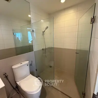Modern bathroom with glass shower enclosure and sleek fixtures in a contemporary apartment.