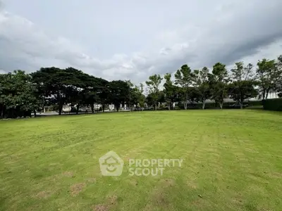 Expansive green lawn with surrounding trees, perfect for outdoor activities and relaxation.