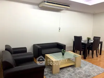 Modern living room with sleek black furniture and dining area, featuring a stylish glass coffee table.