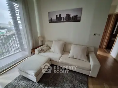 Cozy living room with modern sofa and city view balcony, perfect for relaxation and urban living.