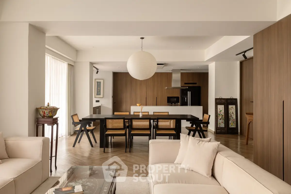Spacious modern living room with open kitchen and elegant dining area, featuring stylish decor and natural lighting.