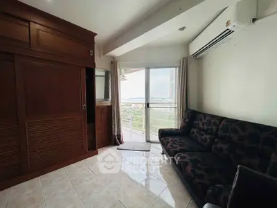 Cozy living room with balcony and sea view, featuring elegant wooden cabinetry and modern air conditioning.