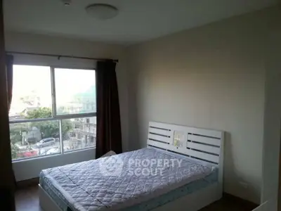 Spacious bedroom with large window and natural light in modern apartment.