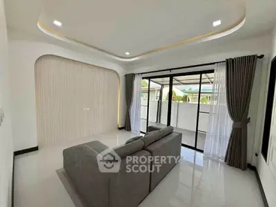 Modern living room with sleek sofa and large windows opening to a spacious balcony.