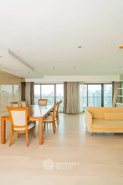 Spacious living room with elegant dining area and city view balcony.