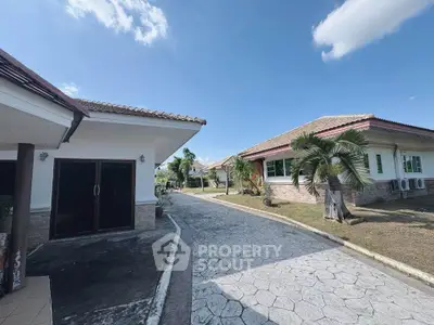Charming suburban houses with spacious driveways and lush greenery under a clear blue sky.