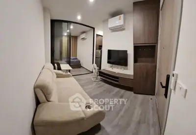 Modern living room with sleek design, featuring a comfortable sofa, flat-screen TV, and air conditioning.