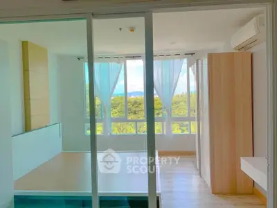 Bright bedroom with large windows and scenic view, featuring modern wooden flooring and built-in wardrobe.
