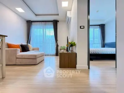 Modern open-plan living room with cozy sofa and adjacent bedroom view.