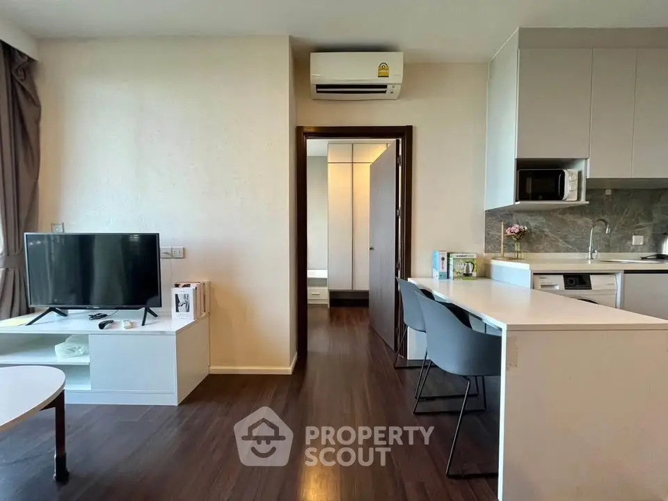 Modern open-plan living room with sleek kitchen and stylish furnishings in a contemporary apartment.