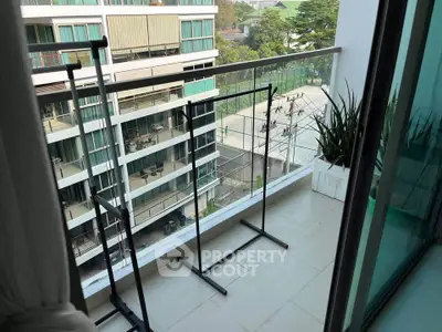 Modern balcony with glass railing overlooking urban landscape and sports court, ideal for city living.