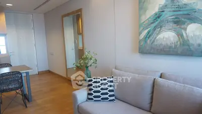 Modern living room with stylish decor and wooden flooring, featuring a cozy sofa and elegant wall art.