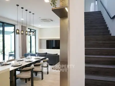 Modern open-plan living room with dining area and staircase in elegant home.