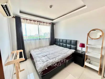 Spacious bedroom with modern decor and large window offering natural light.