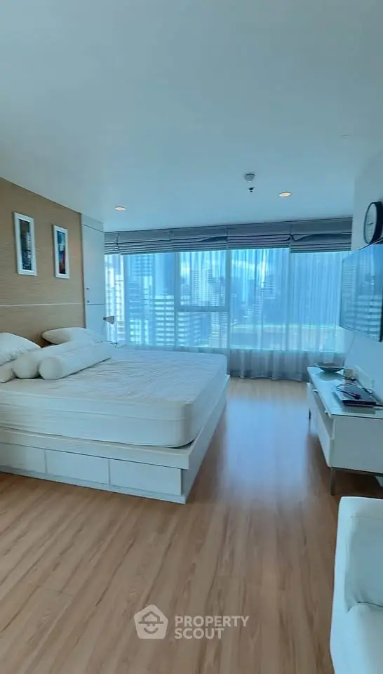 Spacious bedroom with city view and modern decor in high-rise apartment