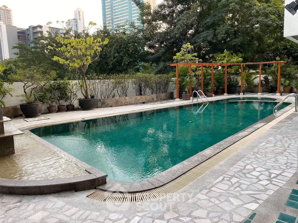 Luxurious outdoor pool area with lush greenery and modern design in urban setting.