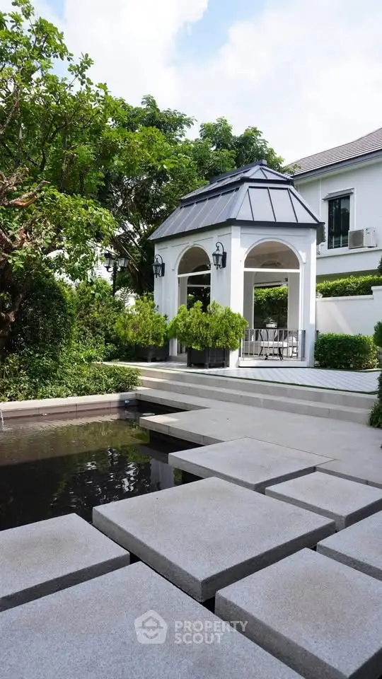 Elegant garden with modern gazebo and stepping stone path in luxury property