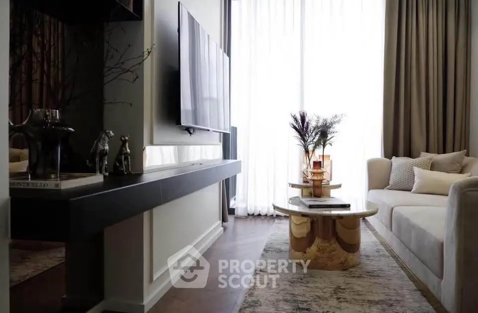 Luxurious living room with modern decor and large TV, featuring elegant furniture and soft lighting.