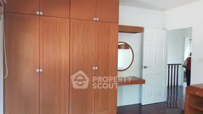 Spacious bedroom with built-in wooden wardrobe and vanity mirror