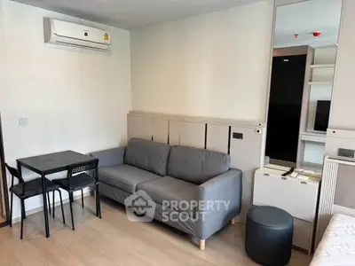 Modern living room with gray sofa, dining table, and air conditioning in a stylish apartment.