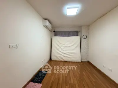 Spacious empty room with wooden flooring and air conditioning, ideal for customization.