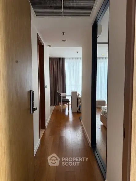 Inviting hallway leading to a bright living area with floor-to-ceiling windows and wooden flooring.