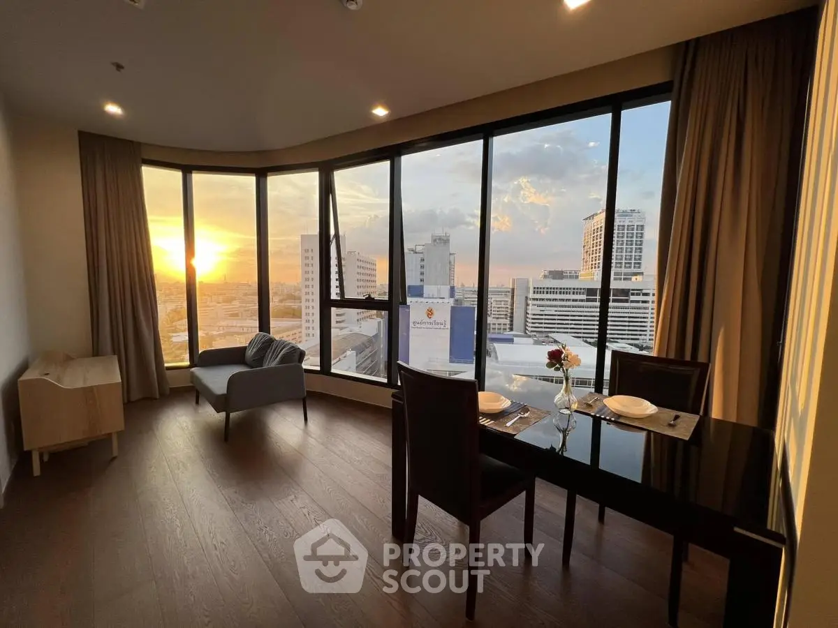 Stunning sunset view from modern high-rise apartment with floor-to-ceiling windows and elegant dining area.