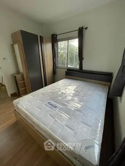 Cozy bedroom with new mattress and wardrobe, featuring a window with natural light.