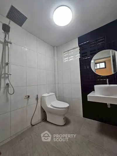 Modern bathroom with sleek fixtures and contemporary design, featuring a shower and stylish sink.