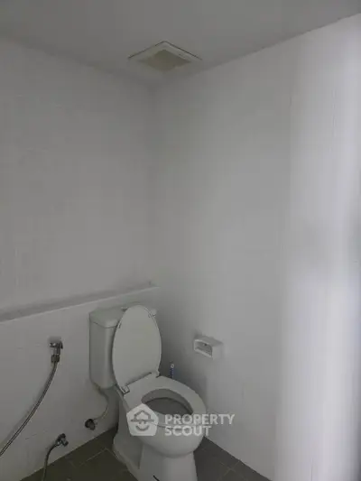 Minimalist bathroom with white tiles and modern toilet in a real estate property.