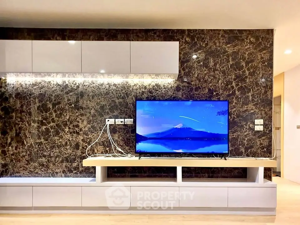Modern living room with marble accent wall and sleek TV setup, perfect for entertainment.